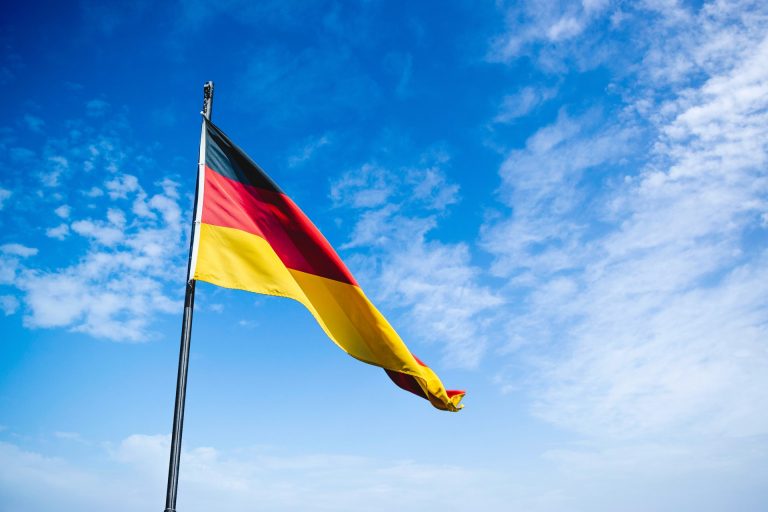 German flag waves with blue sky and clouds in background