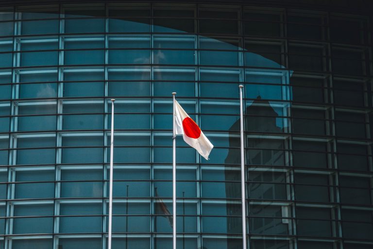 Japanese flag waves in front of building